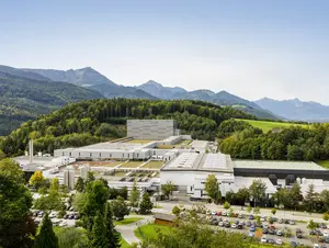 Blick auf das Firmengelände von der Adelholzner Alpenquellen mit Bergpanorama im Hintergrund.