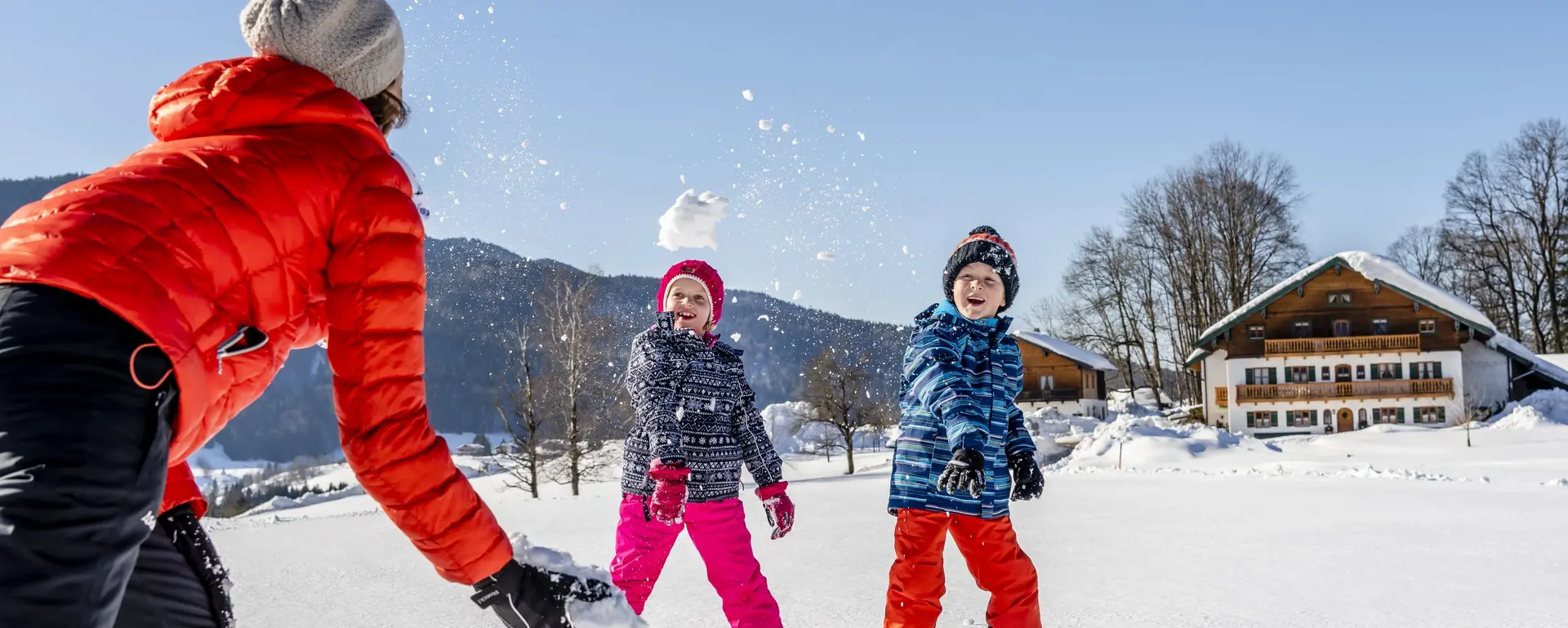 Urlaubsfamilie macht eine Schneeballschlacht in herrlicher Umgebung.