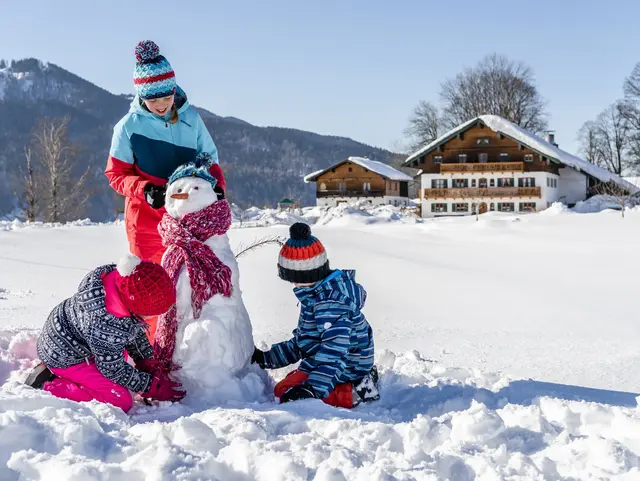 Kinder bauen einen Schneemann