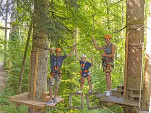 Familie klettert einen Parcour im Kletterwald Prien am Chiemsee.