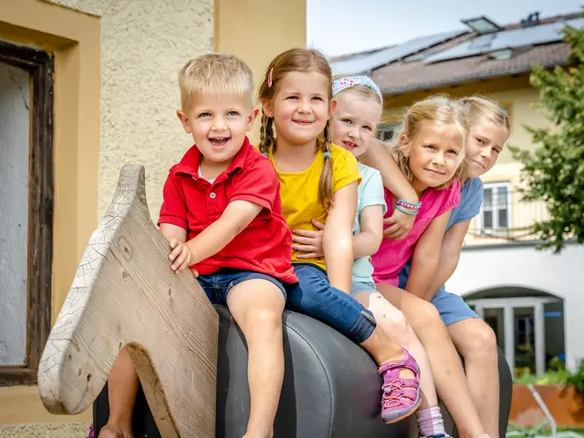 Kinder sitzen auf einen Spiel-Holz-Pferd.