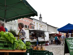 Kunden kaufen frische Lebensmittel auf dem Wochenmarkt in Tittmoning ein.